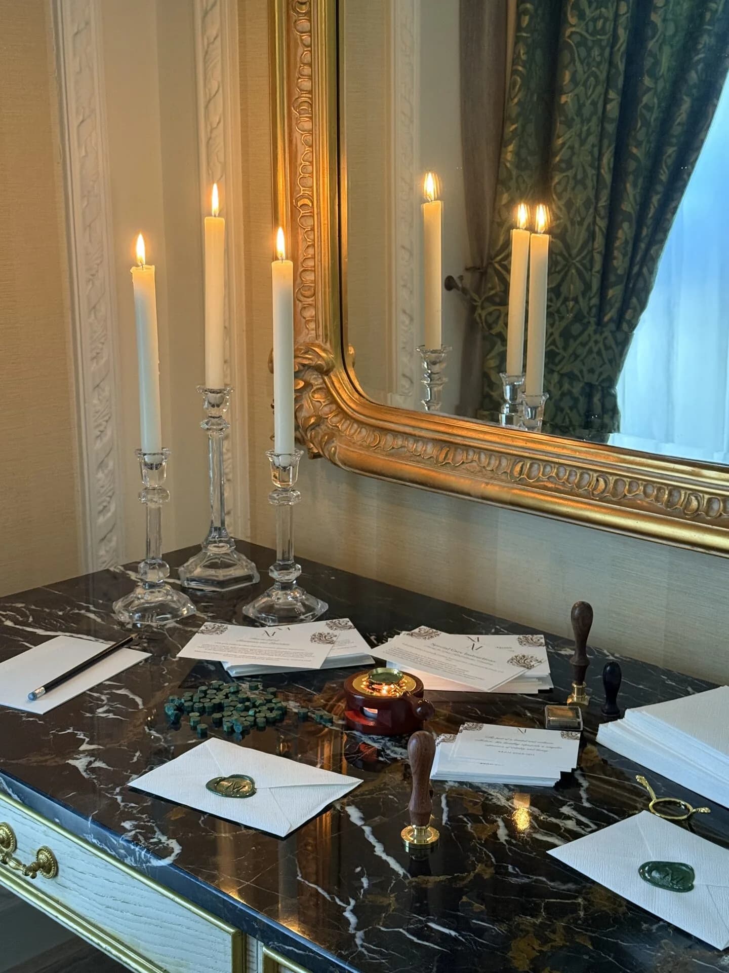 Wax seal desk with crystal candelabras, letters, and stamps on dark marble